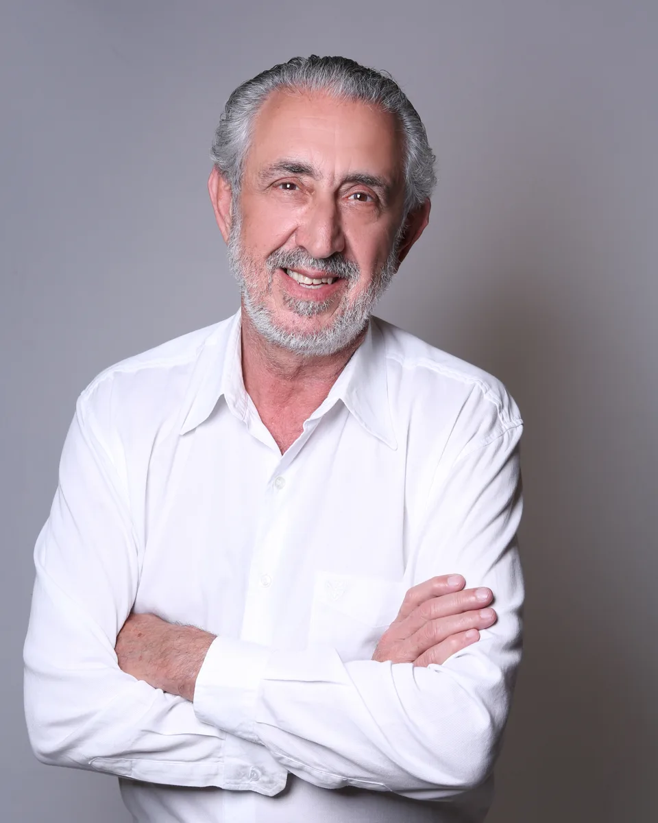 César Damiani de camisa branca, de braços cruzados, sorrindo